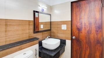 A bathroom with a white toilet, a sink with a mirror above it, and a wooden door.