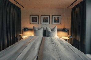 Une chambre à coucher avec un grand lit, trois tableaux encadrés au mur et deux lampes de chevet.