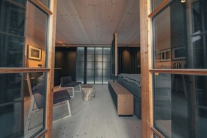 Un intérieur moderne avec un plafond en bois, un lit, un banc, une petite table et un téléviseur.
