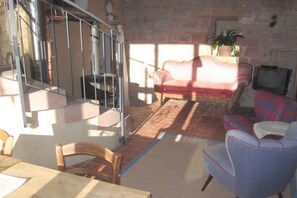 A living room with a red sofa, a blue armchair, a television, and a staircase. - Holiday apartment with 0 bedrooms (Spirkelbach)