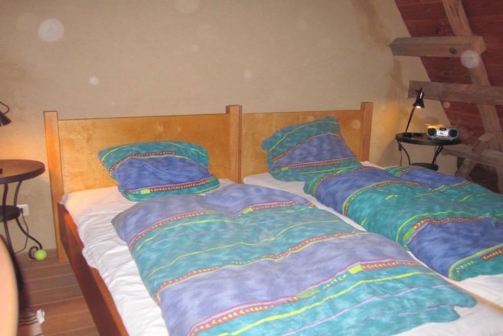 A single bed with a wooden headboard and a colorful blanket.