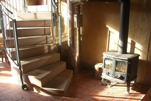 Uma escadaria com corrimão de metal, uma lareira a lenha e piso de azulejos.