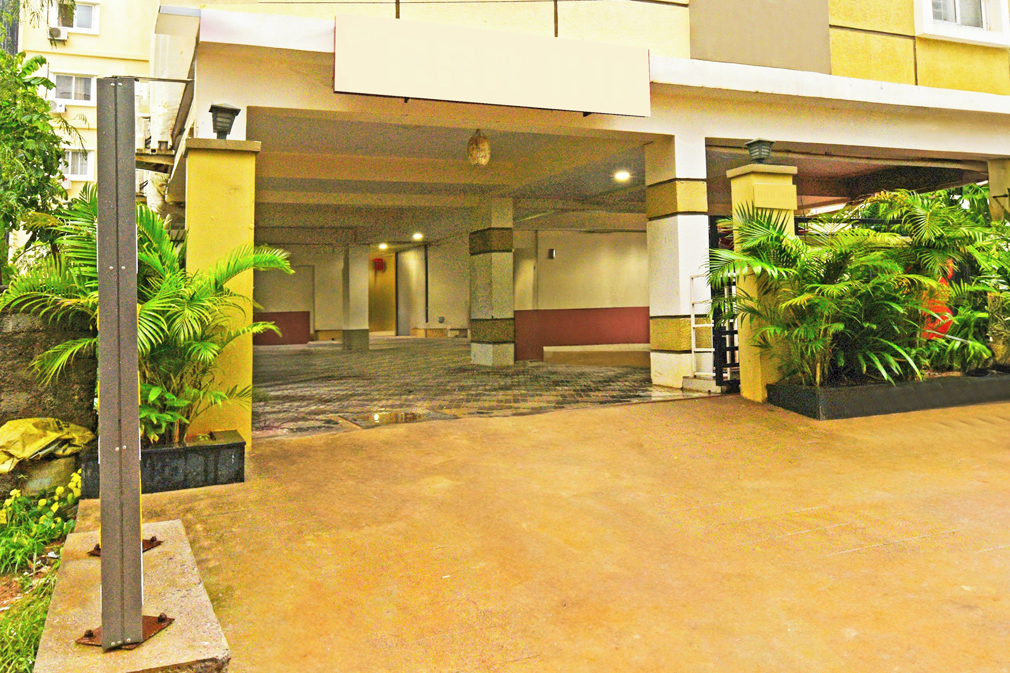 A hotel entrance with a covered walkway, potted plants, and a concrete floor.