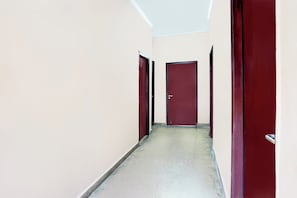 Un pasillo estrecho con dos puertas cerradas, una a cada lado, que conduce a una habitación.