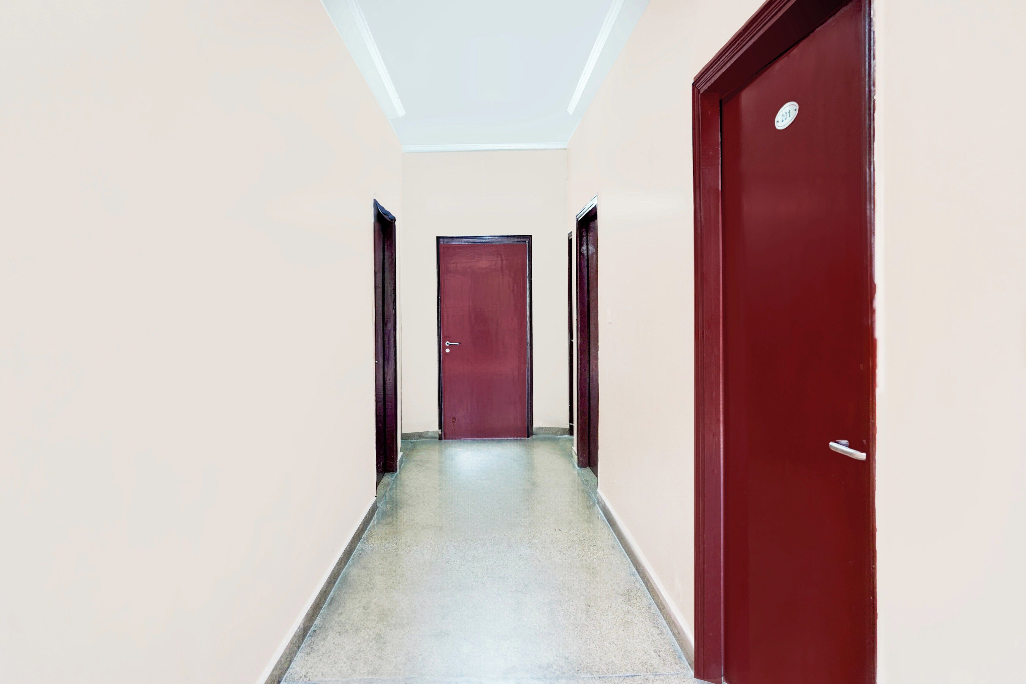 Ein Flur mit einer roten Tür am Ende, einer weißen Decke und einer Lampe.