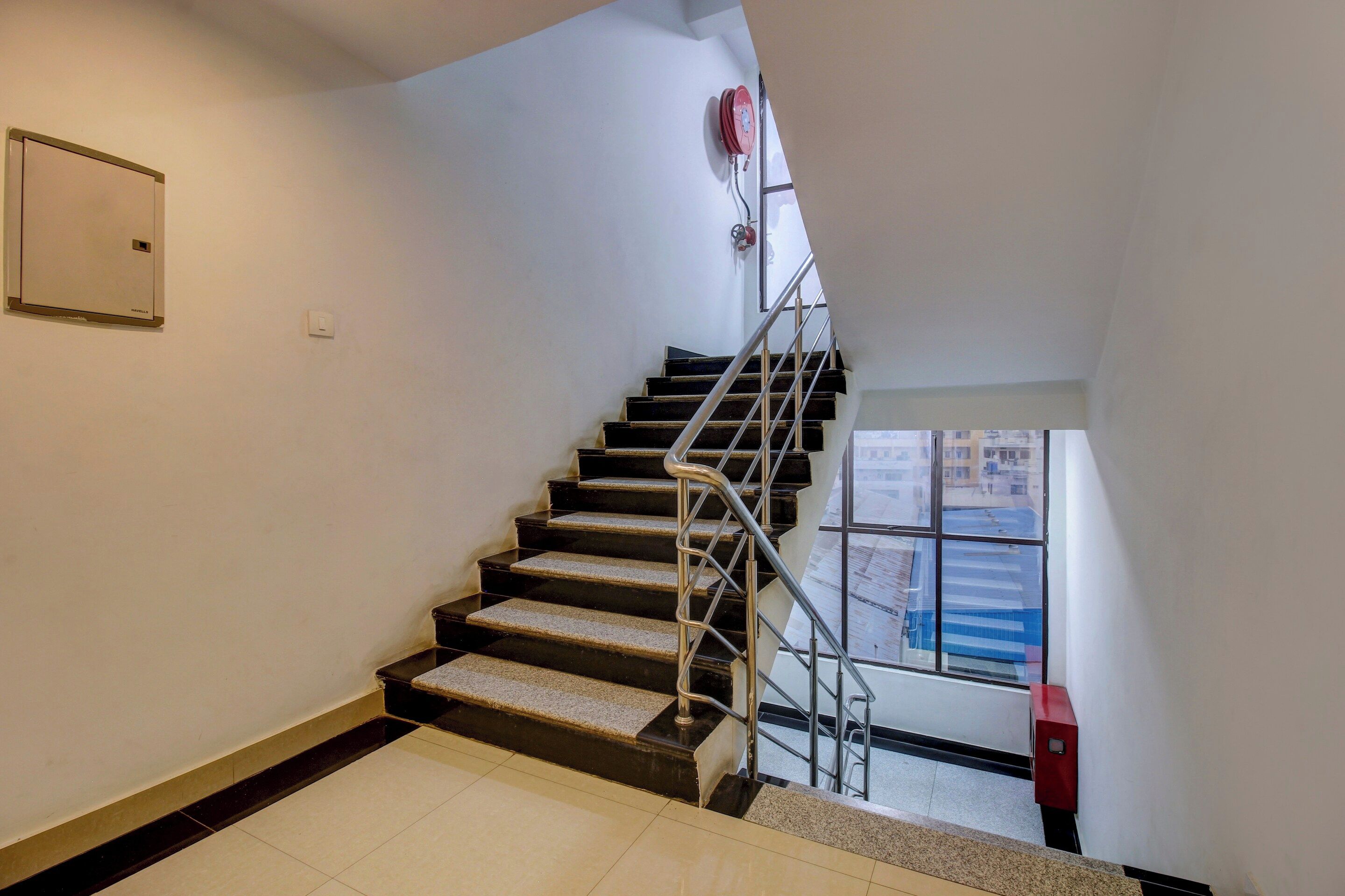 A staircase with metal railings and a fire hose reel on the wall.