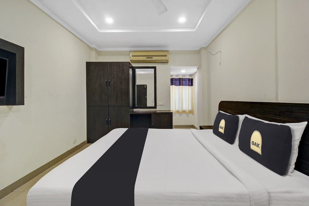 A hotel room with a bed, a wardrobe, a mirror, and a window with curtains.