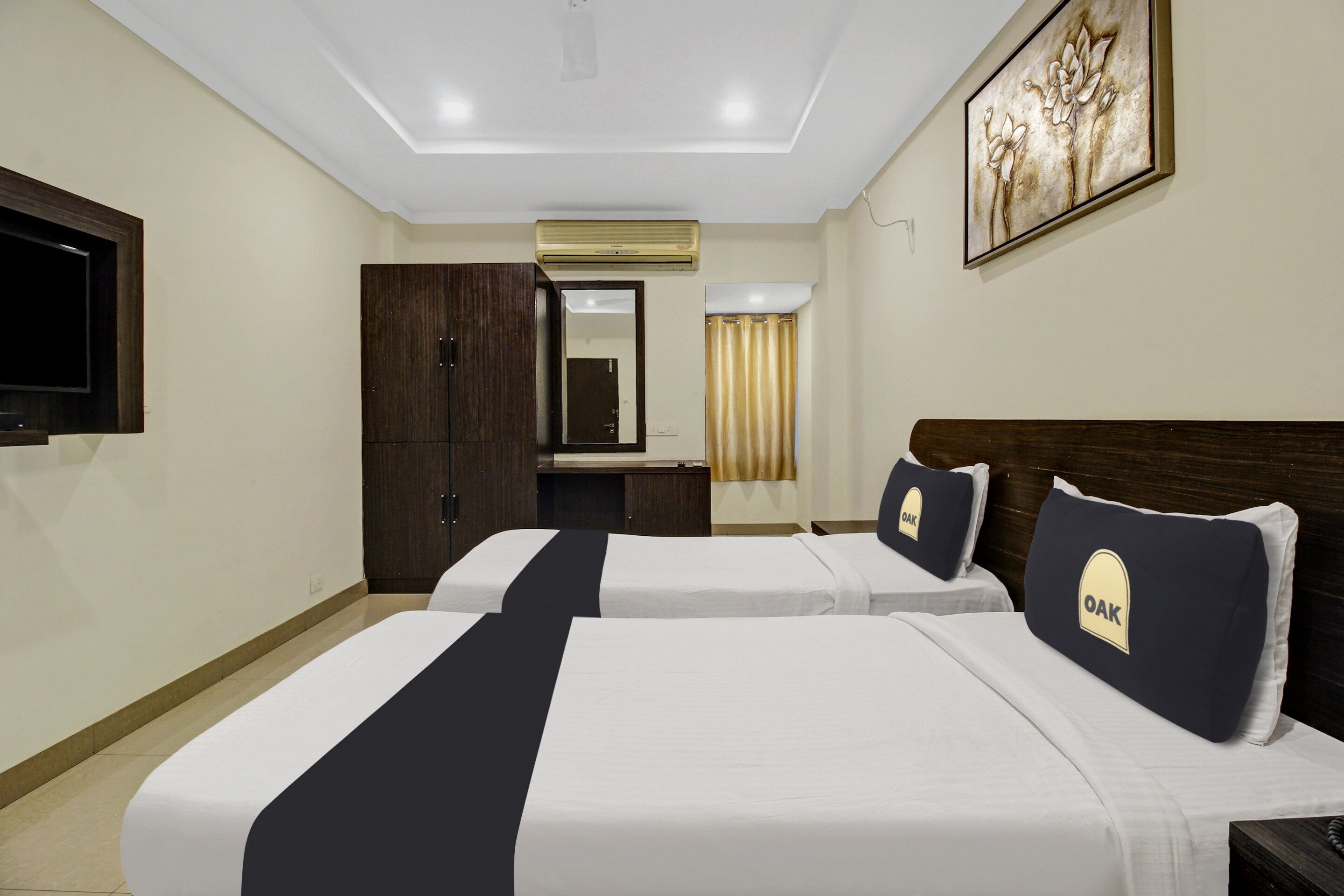 A hotel room with two beds, a flat-screen TV, a wardrobe, an air conditioning unit, and a painting on the wall.