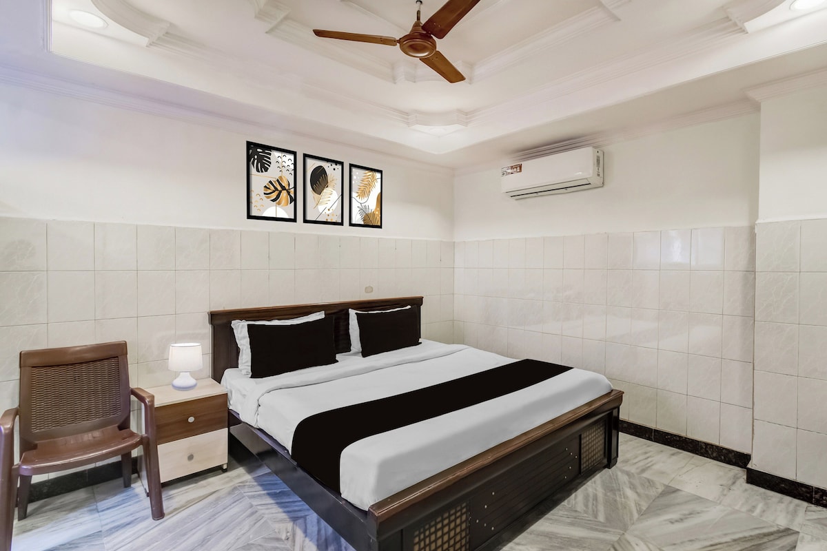 A hotel room with a bed, a chair, a nightstand, and a ceiling fan.
