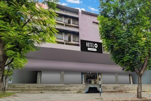 Hotel amb un cartell que indica que ofereix servei per a empreses. Hi ha uns escalons que condueixen a una entrada tancada amb una reixa.