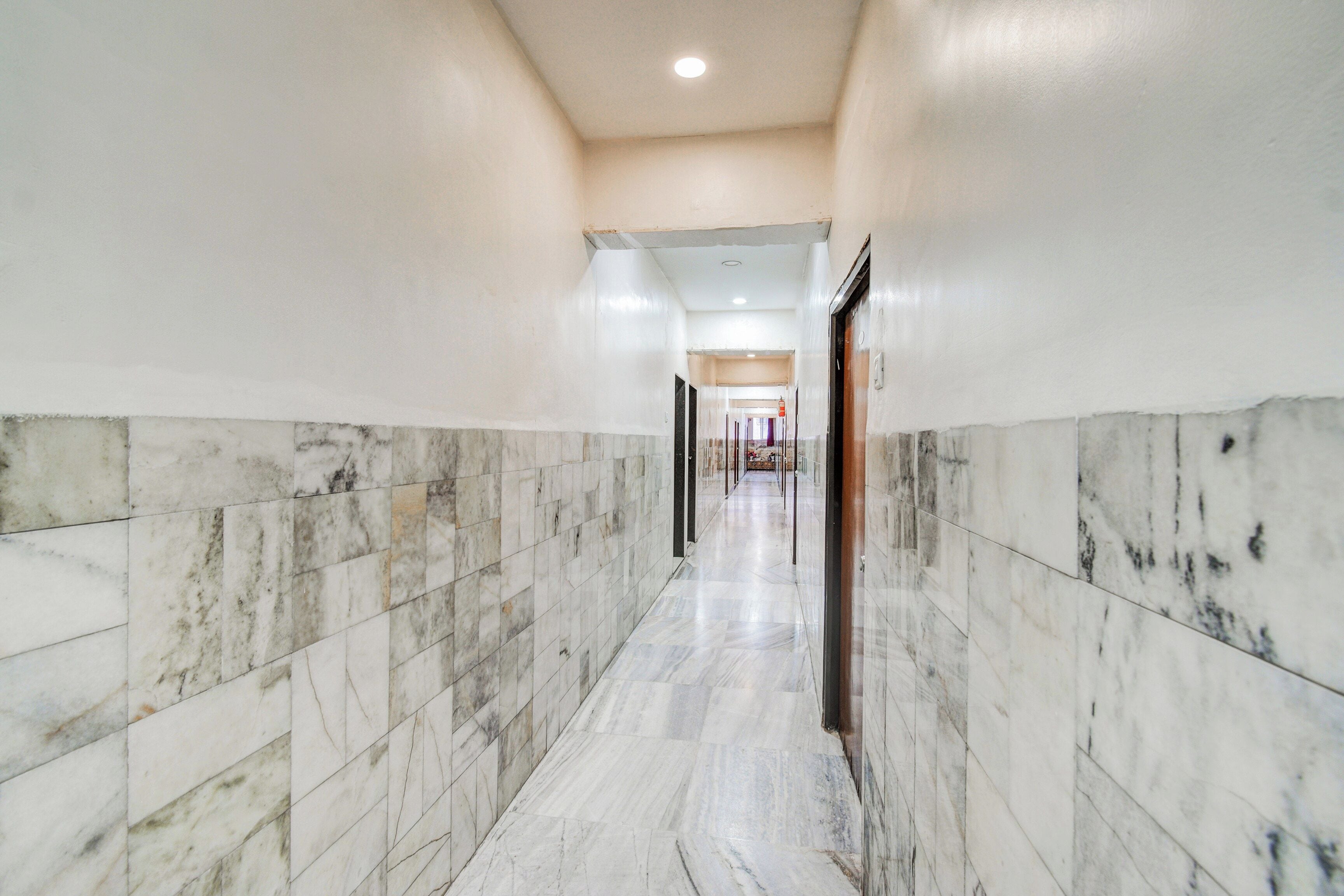 A corridor with marble flooring and walls, leading to a door at the end.