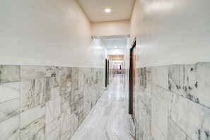 A corridor with marble flooring and walls, leading to a door at the end. - Super Hotel O MG Road Raniganj (Hyderabad)