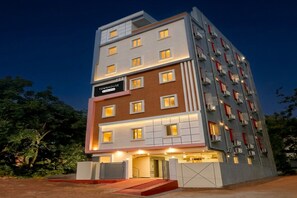 Um hotel com vários andares, uma placa com a inscrição 'TOWNHOUSE' e uma entrada com portão.