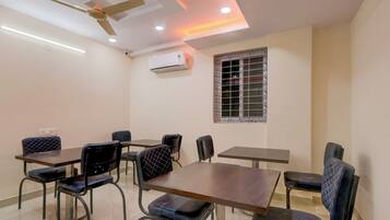 Sala de conferências com ventilador de teto, iluminação embutida, ar condicionado e janela com grades de metal.