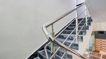 Uma escadaria com corrimão de metal e degraus de mármore.