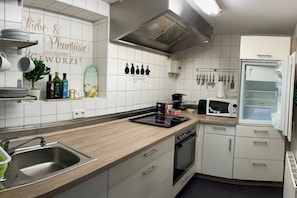 A modern kitchen with white cabinets, a stainless steel sink, a microwave, and a built-in oven. - Holiday apartment with 1 bedroom (Konstanz)
