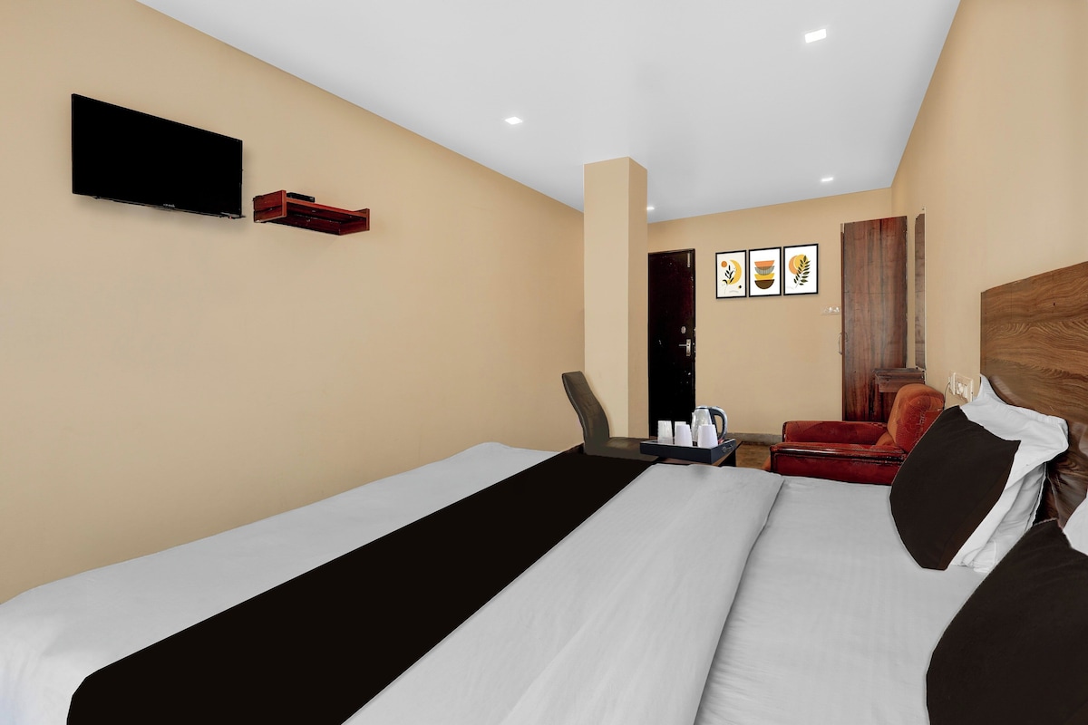 Una habitación de hotel con una cama, un escritorio, una silla, un televisor y obras de arte en la pared.