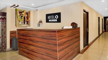 Un mostrador de recepción de hotel con detalles de madera, una señal encima y un cuadro en la pared.