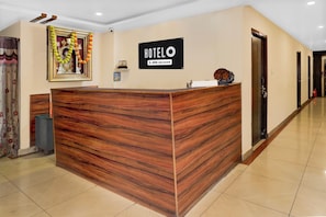 Un mostrador de recepción de hotel con detalles de madera, una señal encima y un cuadro en la pared.