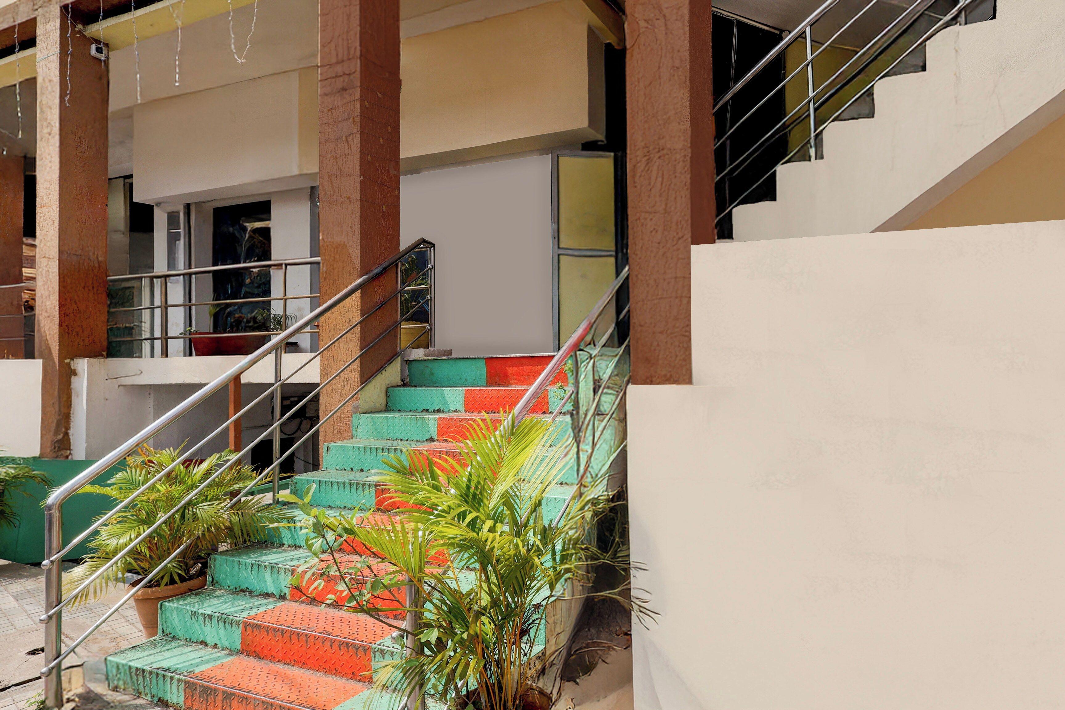 Una escalera con peldaños de colores alternados, barandillas de metal y plantas en macetas.