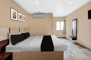 Una habitación de hotel con una cama grande, una mesita de noche, un espejo y una ventana.