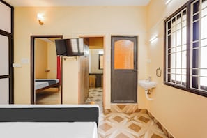 Een hotelkamer met een bed, een televisie, een badkamer met een wastafel en een raam met tralies.