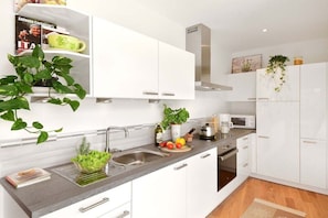 A modern kitchen with white cabinets, a grey countertop, and a stainless steel range hood. - Holiday apartment in Merano with swimming pool (Meran)