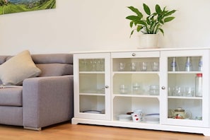 A living room with a grey sofa, a white cabinet with glass doors, and a potted plant on top. - Holiday apartment in Merano with swimming pool (Meran)