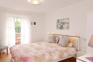 A bedroom with a bed, a chair, a nightstand, a lamp, and a painting on the wall. - Holiday apartment in Merano with swimming pool (Meran)
