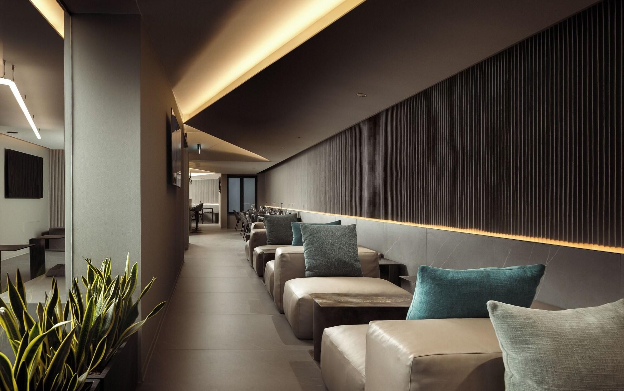 A modern interior with a long corridor, seating area with cushions, and a wall with vertical lines.