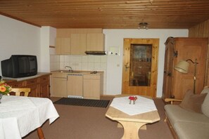 A compact living space with a kitchenette, a dining table, a sofa, and a television. - Holiday apartment in Bad Wiessee with parking (Bad Wiessee)