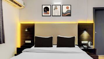 Habitación de hotel con una cama grande, dos mesitas de noche, un equipo de aire acondicionado y tres cuadros en la pared.