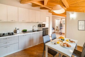 A modern kitchen with white cabinets, a dining table with chairs, and a breakfast setting. - In the heart of the city, adjacent to the central Piazza del Popolo, at the gates of the historic center and close to the tree-lined avenue that leads to the sea, Il Maestrale is a delightful newly built attic, ready to accommodate up to 4 people.Withi (Albenga)