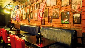 A restaurant with brick walls, framed posters, and red and black leather seating.