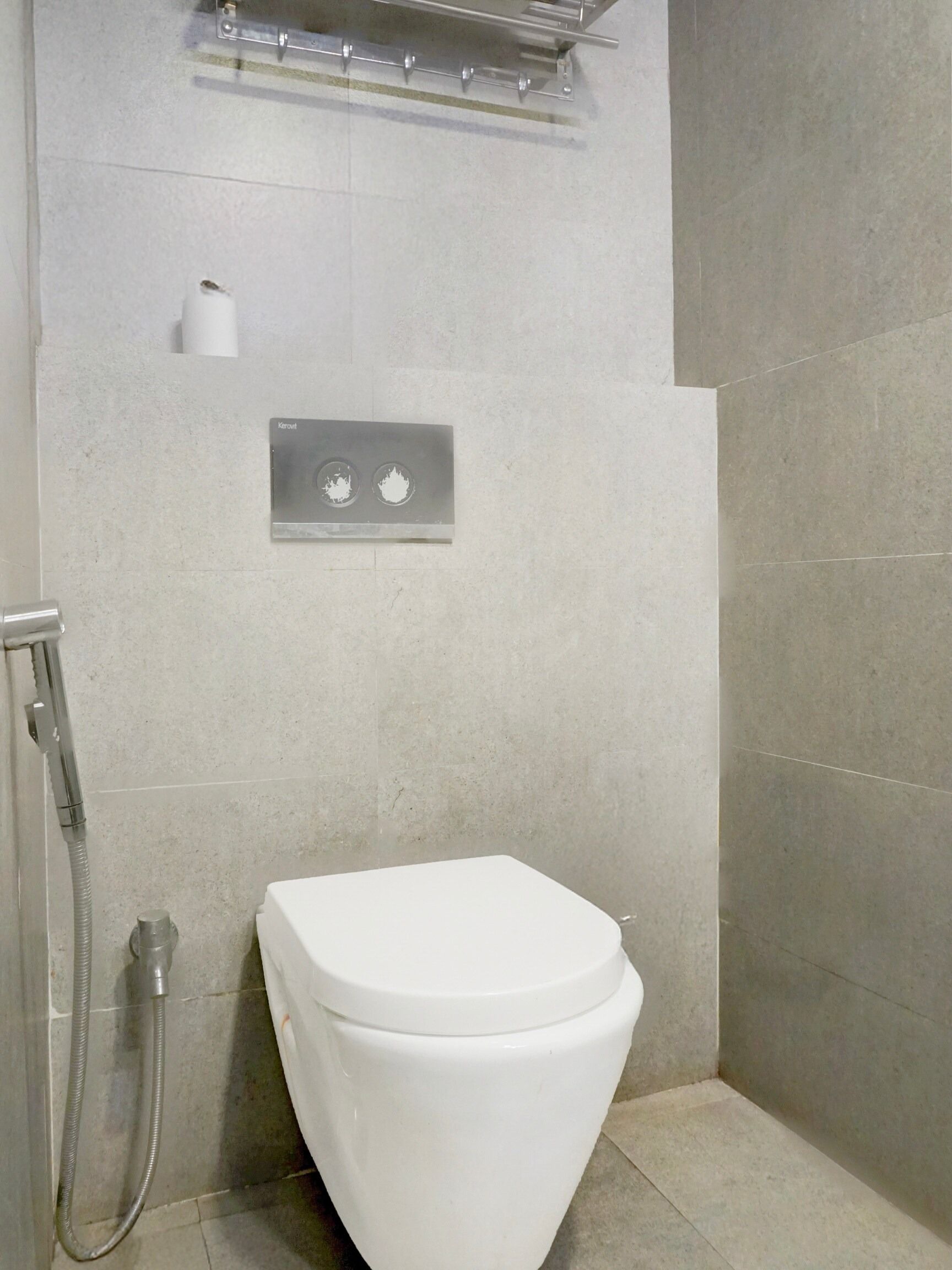 A bathroom with a toilet, a shower, and a control panel.