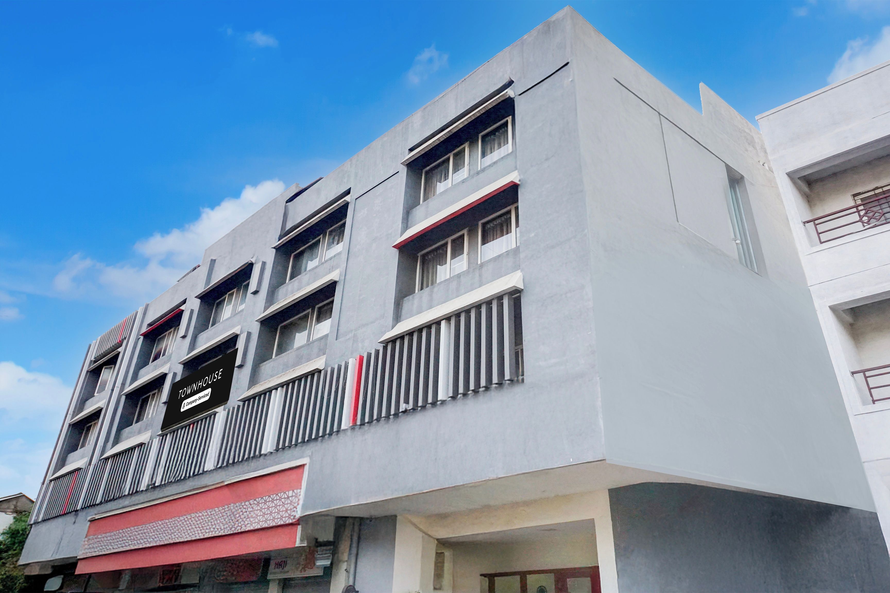 A multi-story building with a modern architectural design, featuring balconies and a prominent signage indicating a commercial service.