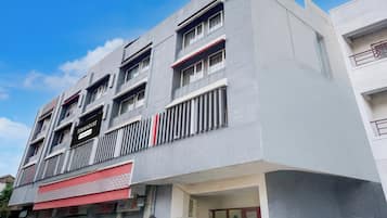 A multi-story building with a modern architectural design, featuring balconies and a prominent signage indicating a commercial service.