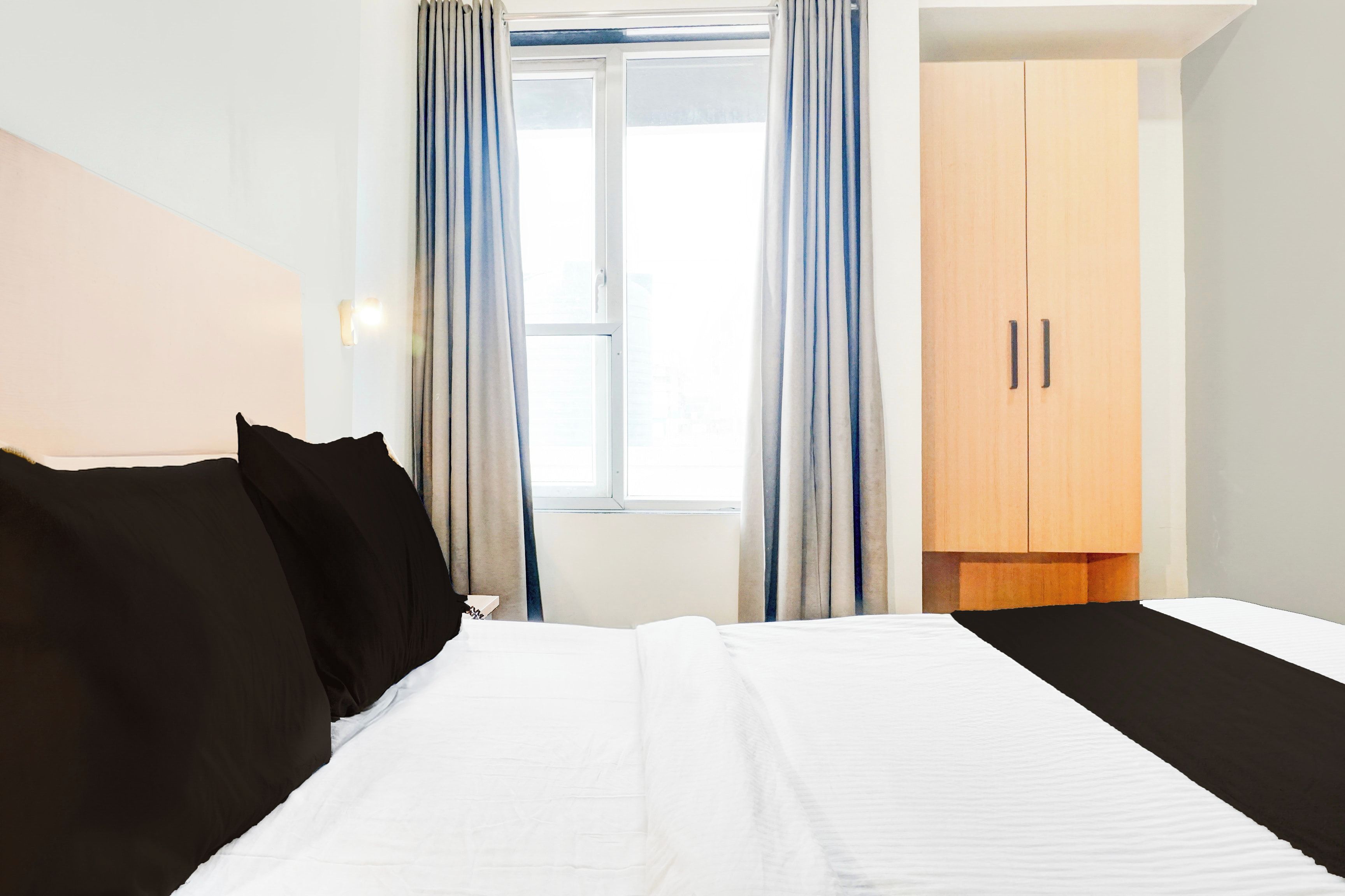 A hotel room with a bed, a wardrobe, and a window with curtains.