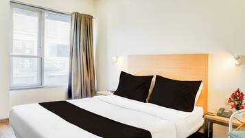 A hotel room with a bed, a nightstand, a telephone, and a window with curtains.
