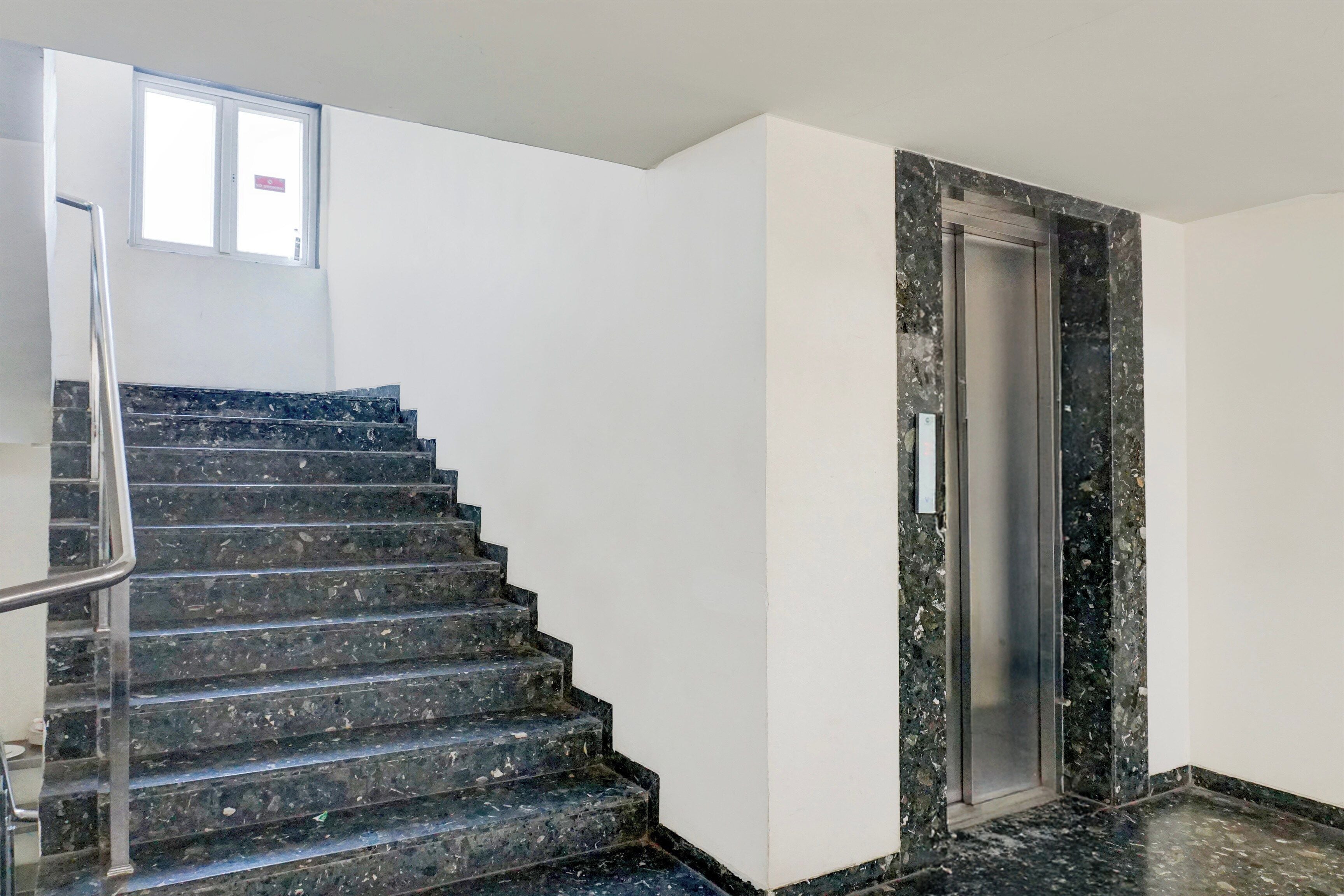 Una escala amb barana metàl·lica que porta a una porta amb estructura metàl·lica.