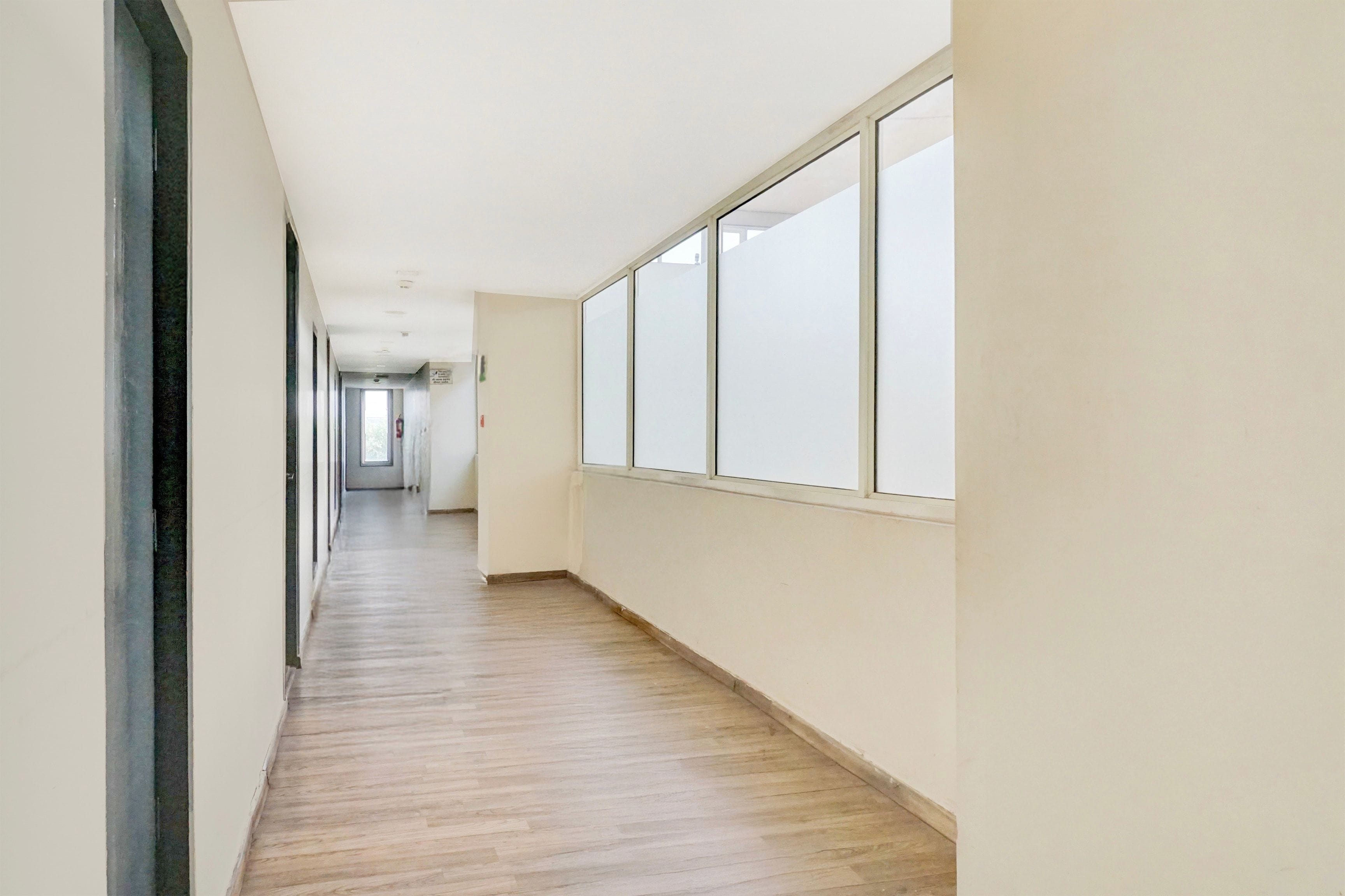A long, narrow hallway with a wooden floor and large windows on one side.