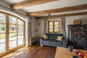 A room with wooden beams, a sofa, a cabinet with floral patterns, and a table with fruit. - Home - Apartment Liesl (Surberg)