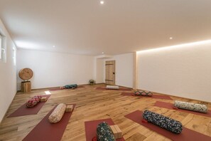 Un studio de yoga doté d’un plancher en bois, de tapis rouges et de meubles en bois.