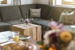 A cozy living area with a grey sofa, a wooden coffee table, and a vase with flowers. - Home - Apartment Ludwig (Surberg)