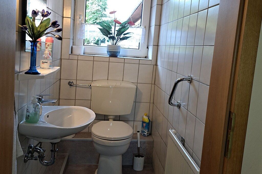 A small bathroom with a toilet, sink, and window.