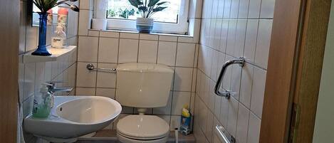 A small bathroom with a toilet, sink, and window.