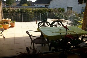 A patio with a table and chairs, surrounded by potted plants and a metal fence. - Holiday apartment with 1 bedroom (Bispingen)