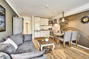 Un espacio habitable moderno con sofá, mesa de comedor, sillas, una mesa de centro y una cocina.