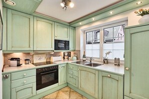 A kitchen with teal cabinetry, a microwave, a stove, and a sink. - Holiday apartment with 3 bedrooms (Westerland)