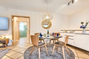 A modern dining area with a round table, chairs, and a chandelier. - Holiday apartment with 3 bedrooms (Westerland)